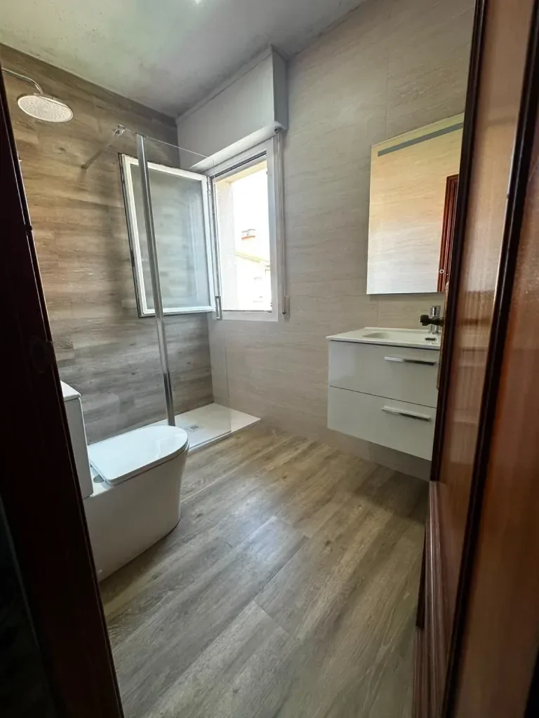 Baño renovado con mueble de lavabo suspendido y plato de ducha