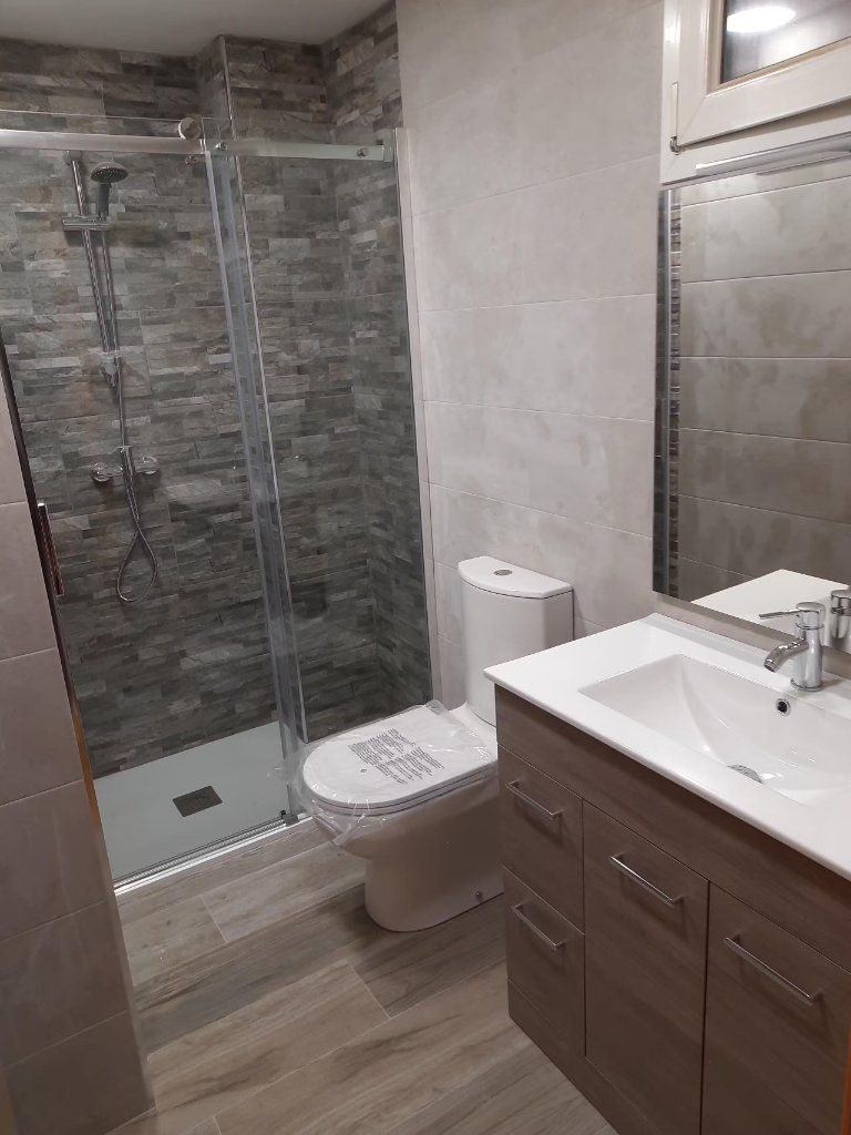 Mueble de lavabo de madera junto a ducha acabada en piedra