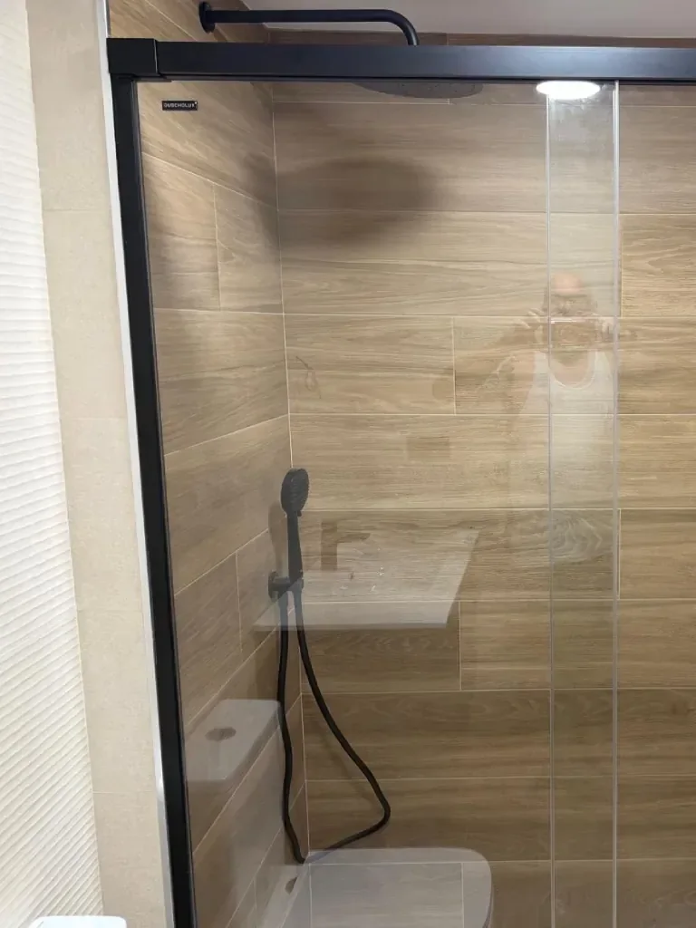 Ducha en piedra gris con mueble de lavabo y toallero