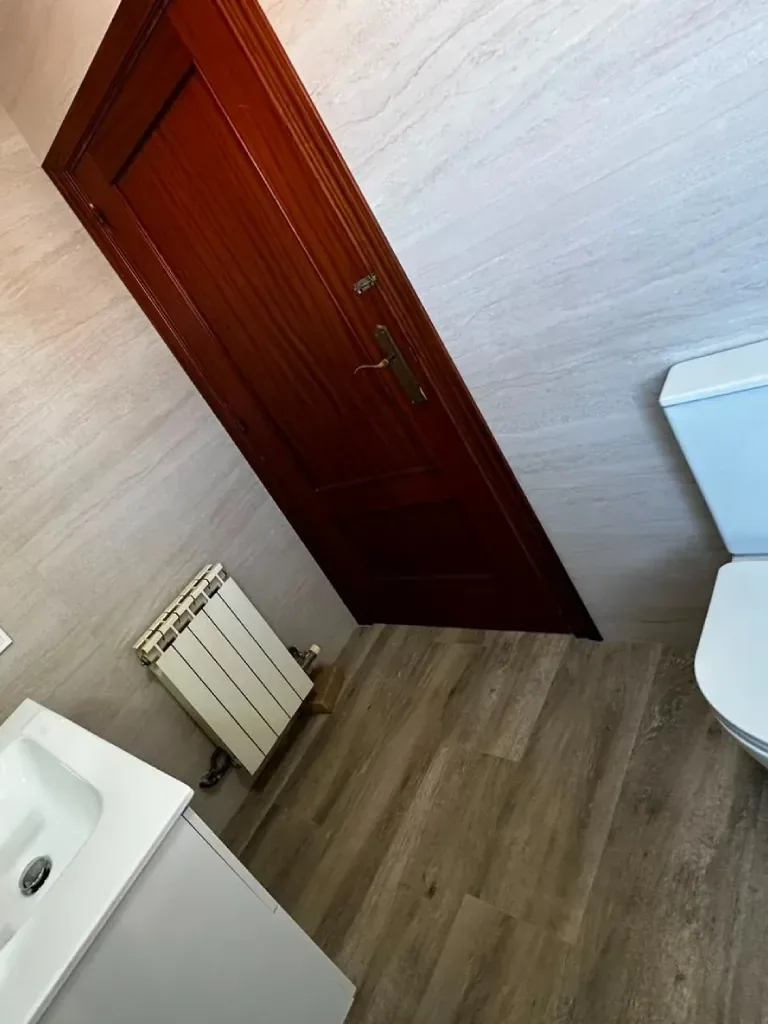 Baño terminado con toallero radiador y suelo laminado