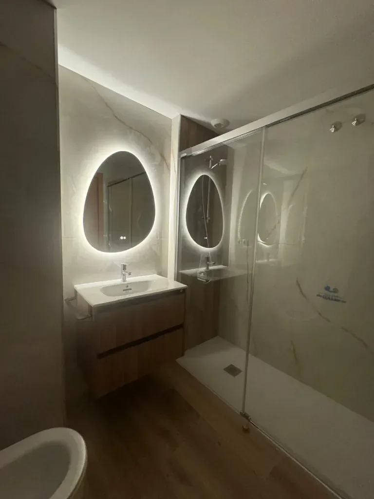 Espejos redondos con luz integrada frente a la zona de ducha