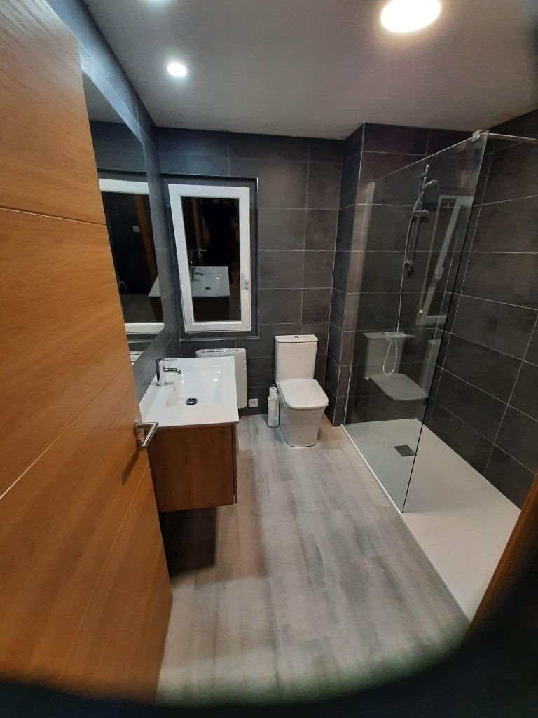 Baño con mampara corredera y pavimento laminado